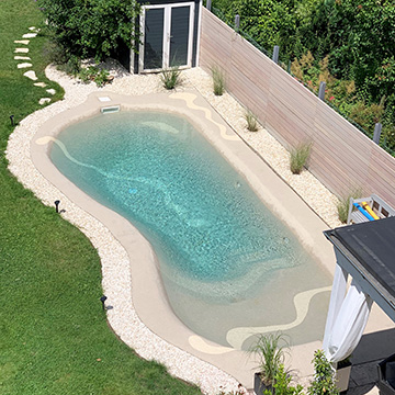 Ein Beachpool in einem Garten mit vielen Pflanzen, einer Hütte, einem Schrank und Sitzmöglichkeiten